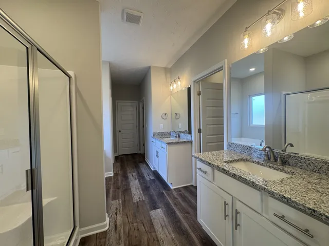 a bathroom with a granite countertop sink a mirror and a shower