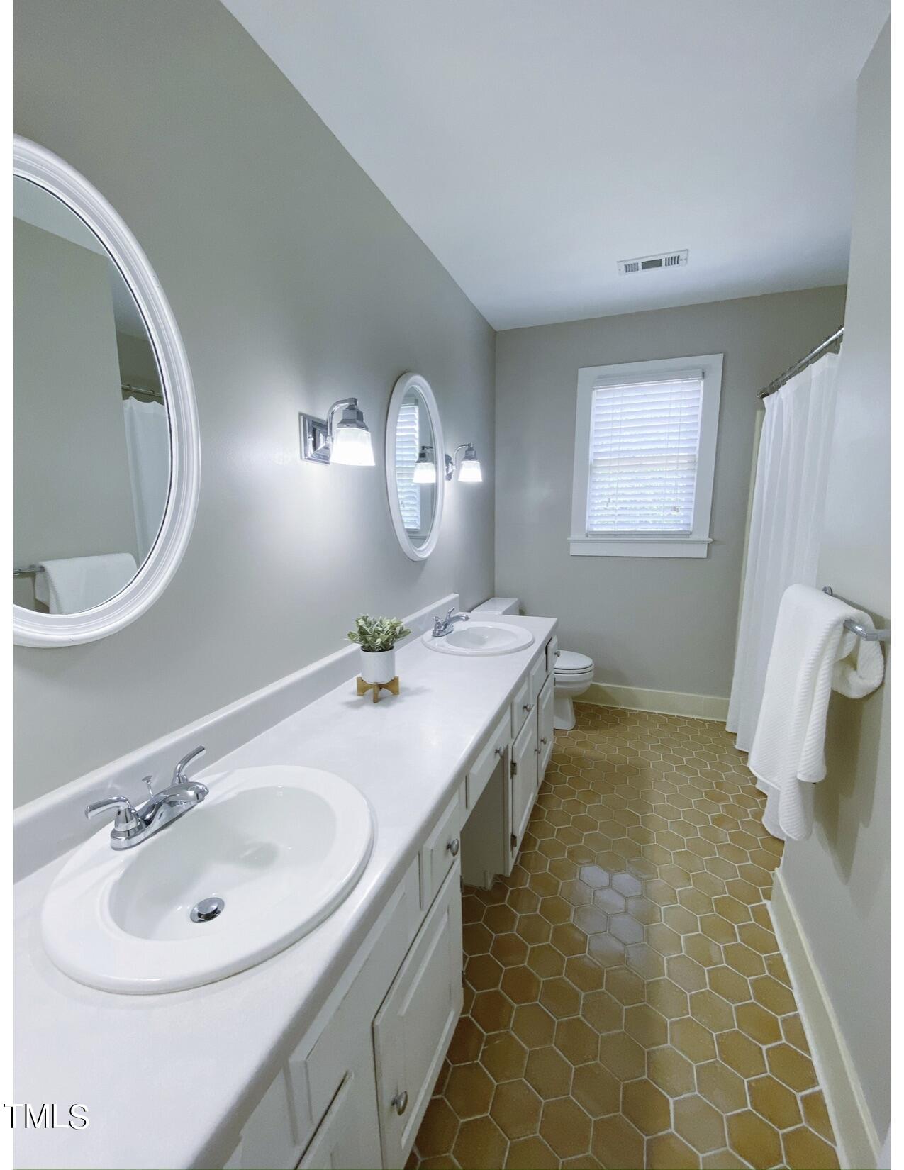 2000 Cayuga Place Raleigh, NC 27612 - Photo 27 of 31 a bathroom with a double vanity sink and a mirror
