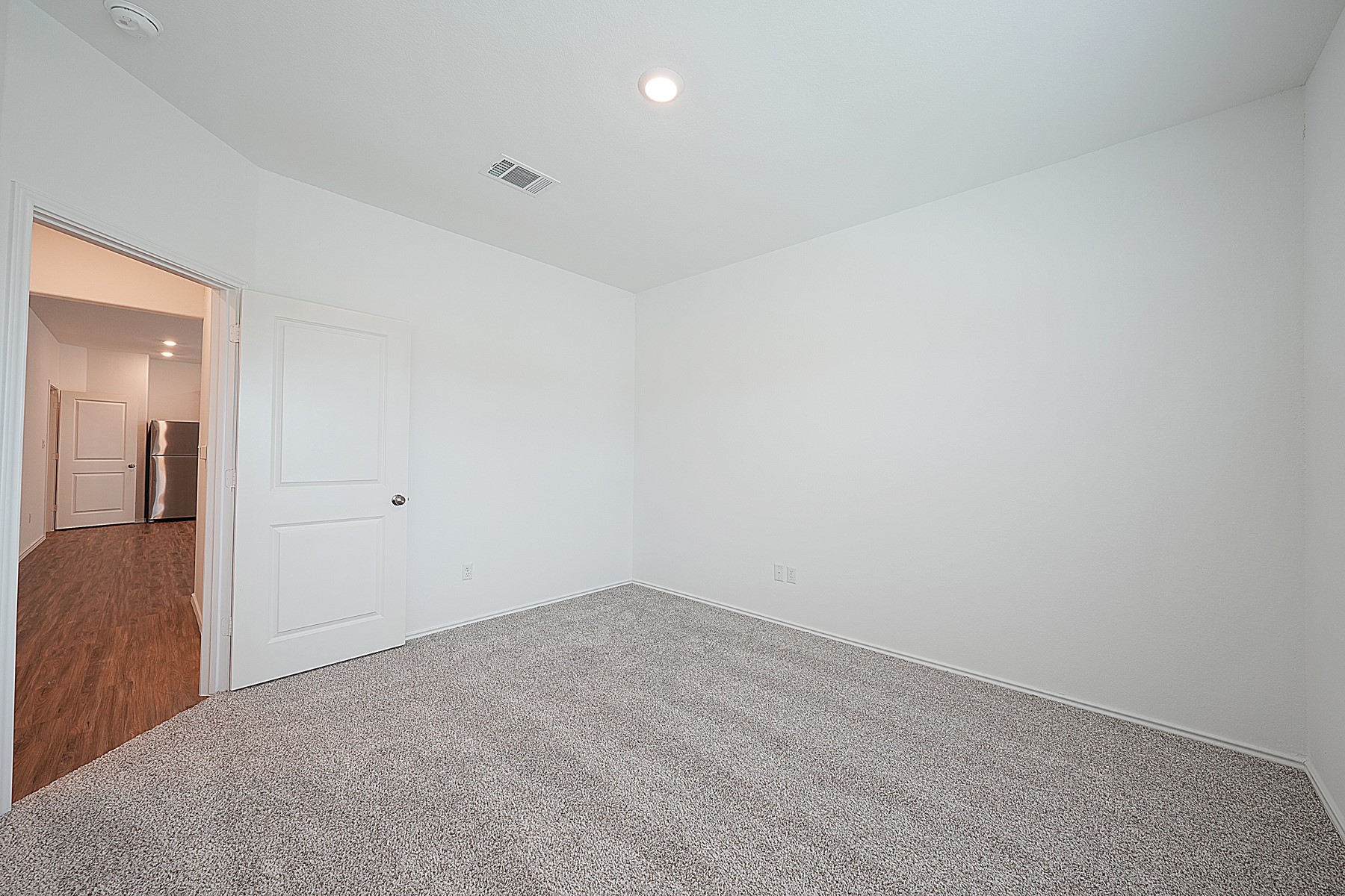932 Mallow Road Leander, TX 78641 - Photo 11 of 34 A well-lit, neutral-toned room featuring plush carpeting and a clear view into an adjacent kitchen space.