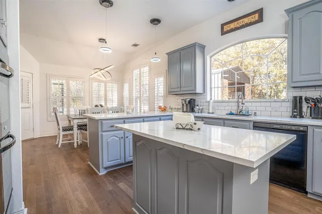 a kitchen with center island a sink dishwasher a stove and a dining table with wooden floor