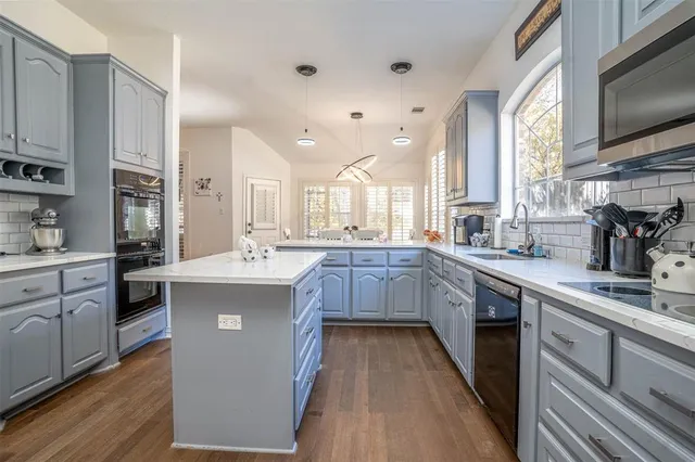 a kitchen with kitchen island granite countertop a sink appliances cabinets and a counter top space