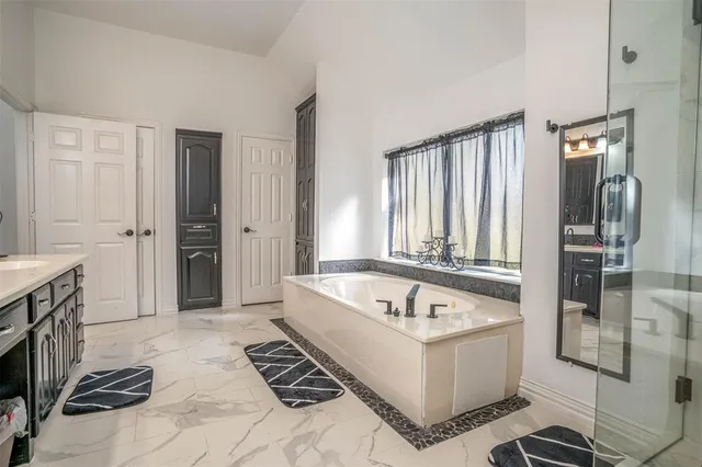 a spacious bathroom with a tub a sink and a mirror