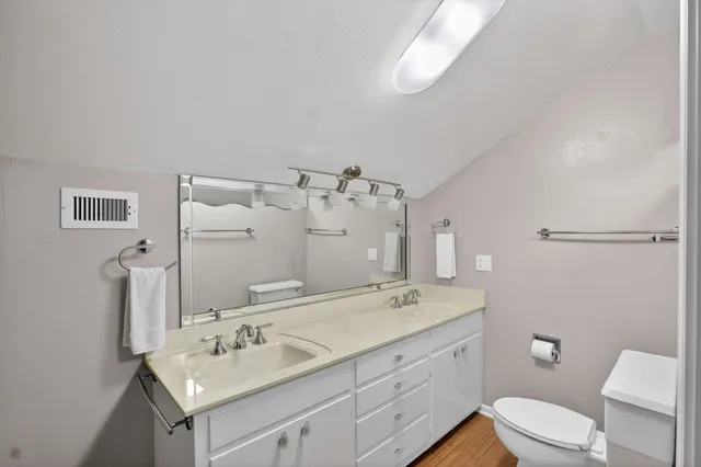 a bathroom with a double vanity sink and mirror with toilet