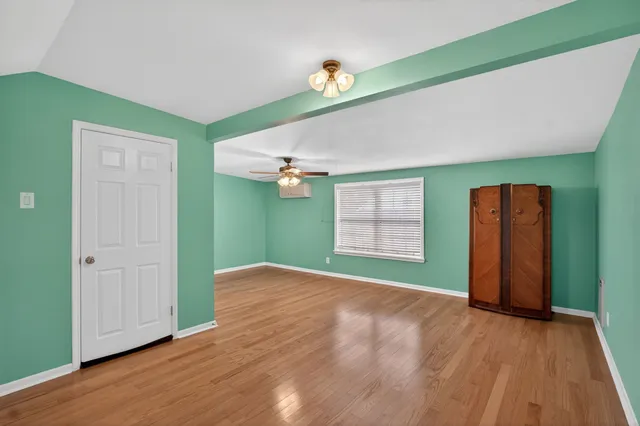 a view of an empty room with window and wooden floor