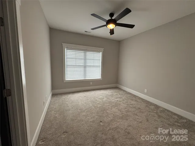 an empty room with closet and a ceiling fan