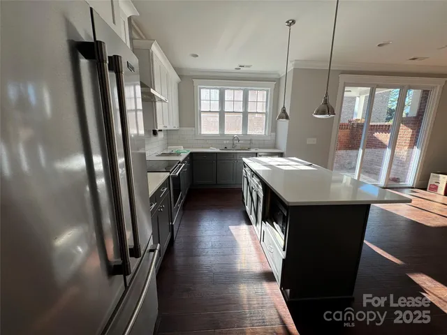 a kitchen with stainless steel appliances granite countertop a refrigerator a sink dishwasher a stove and white countertops with wooden floor