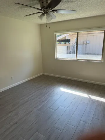 an empty room with wooden floor fan and windows