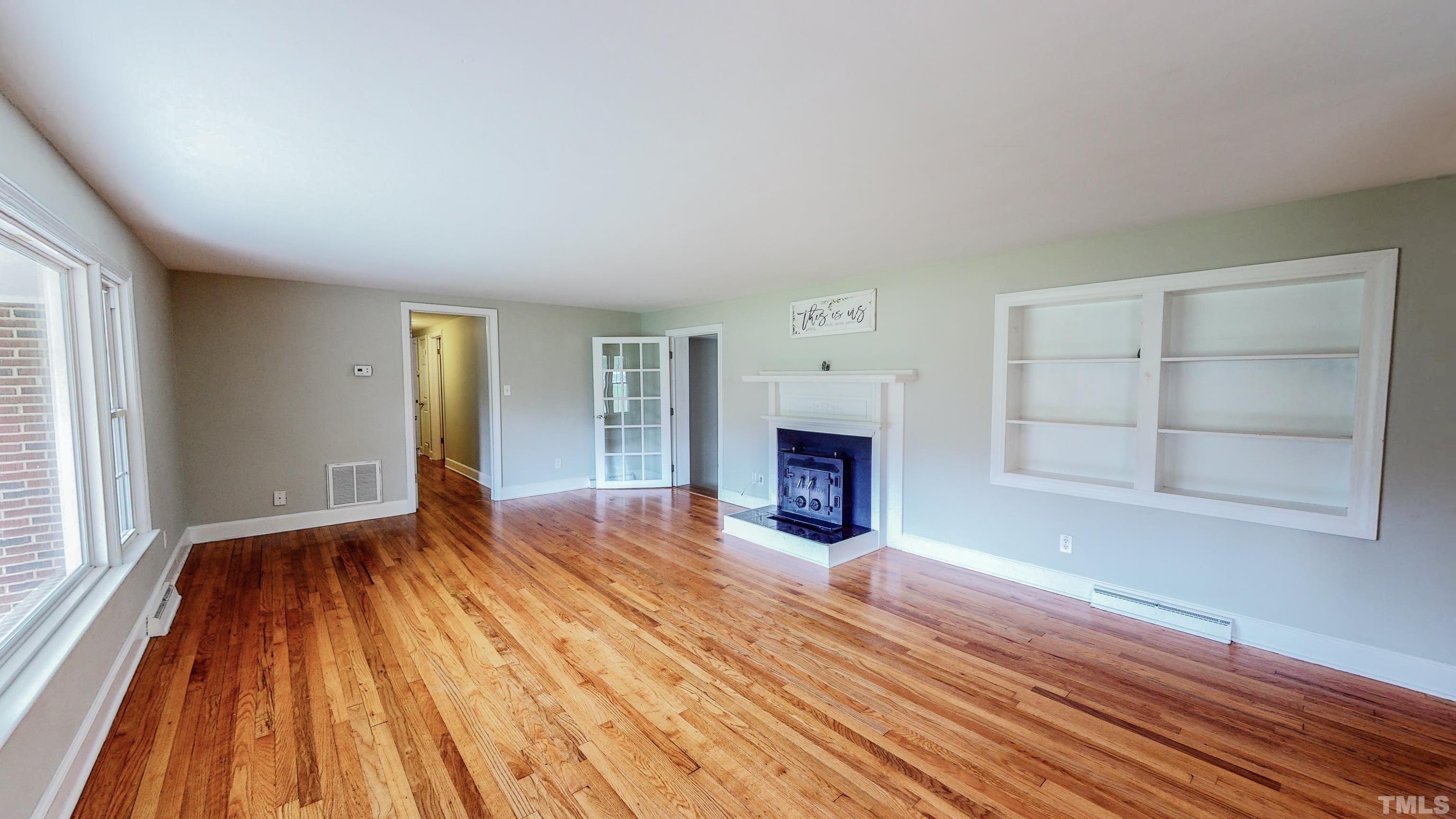 3920 Oxford Road Roxboro, NC 27574 - Photo 2 of 30 an empty room with wooden floor fireplace and windows