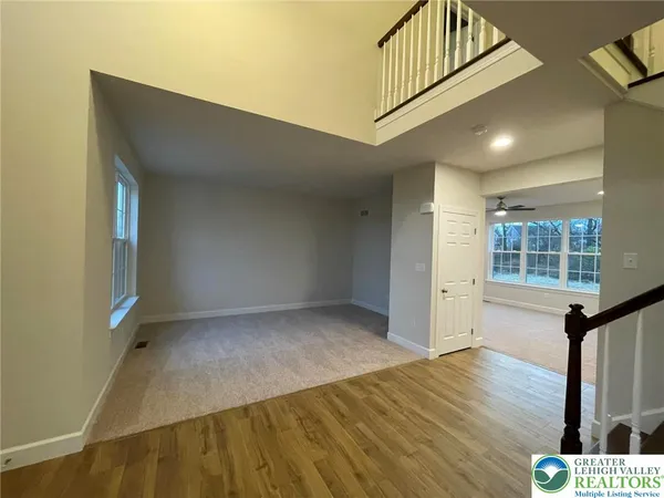 a view of an empty room with window and wooden floor