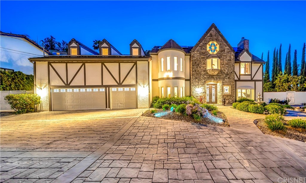 22963 Cass Avenue Woodland Hills, CA 91364 - Photo 2 of 66 a view of a brick house with large windows and a yard with plants