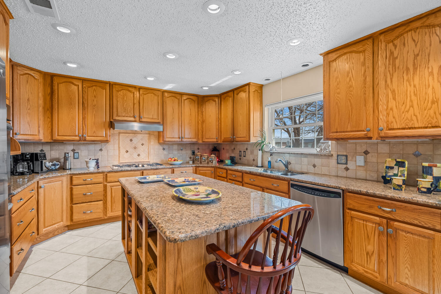1500 West Lynn Street Slaton, TX 79364 - Photo 12 of 37 a kitchen with stainless steel appliances granite countertop wooden cabinets a sink a stove a dining table and chairs