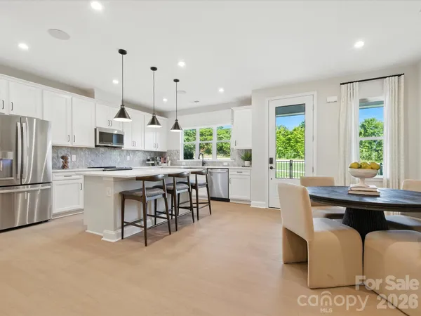 a kitchen with stainless steel appliances kitchen island granite countertop a table chairs microwave and sink