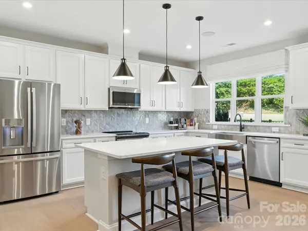a kitchen with stainless steel appliances granite countertop a stove a sink a refrigerator a center island a stove and a window