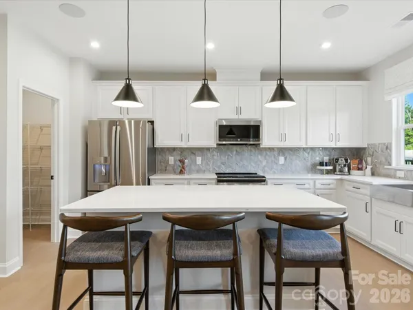 a kitchen with stainless steel appliances kitchen island a table and chairs in it