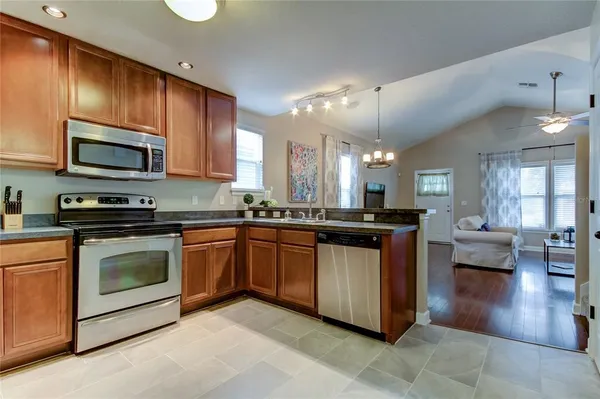 a kitchen with stainless steel appliances granite countertop a stove top oven a sink dishwasher a dining table and chairs