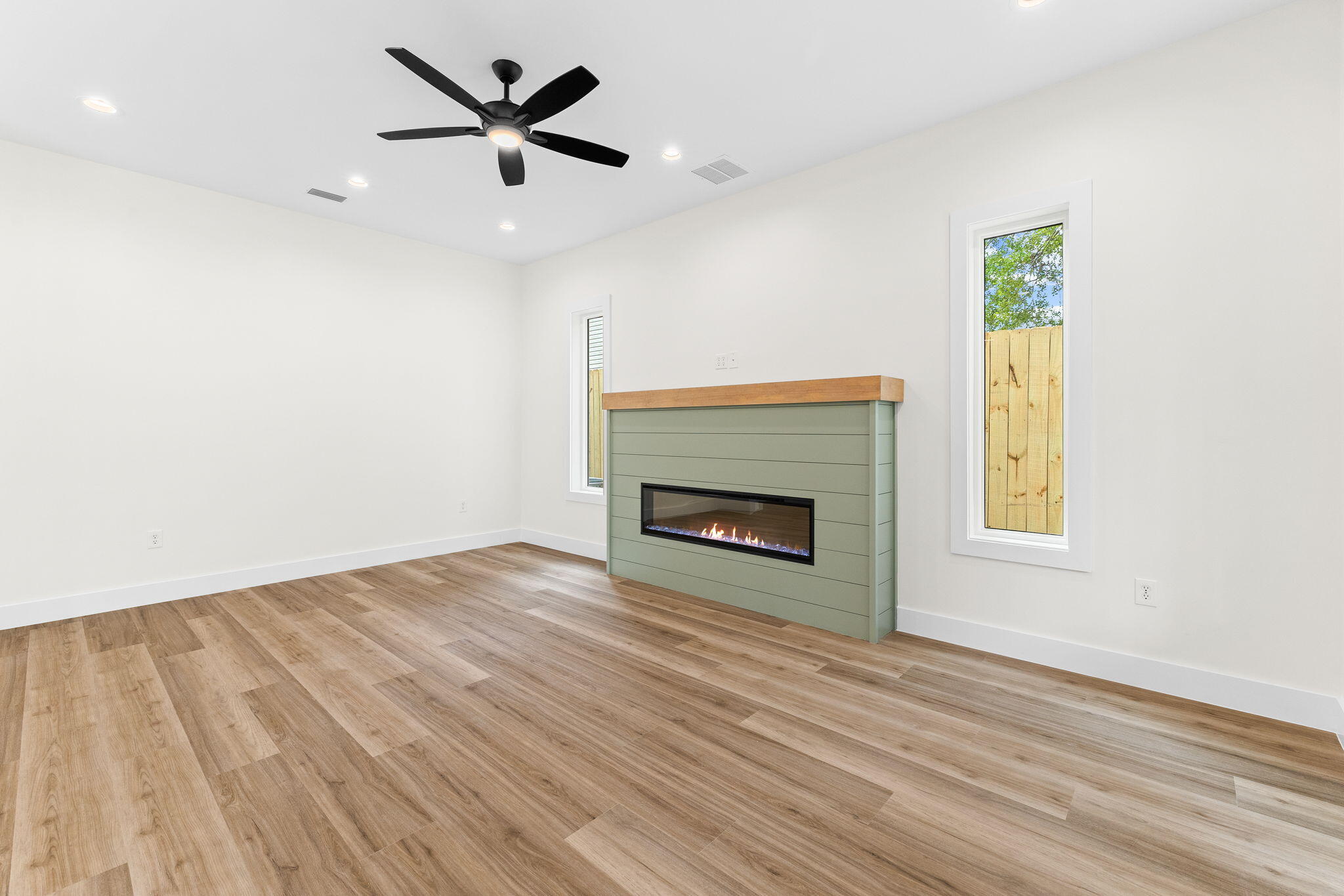 22 Georgie Street Point Washington, FL 32459 - Photo 29 of 57 an empty room with windows a fireplace and a ceiling fan