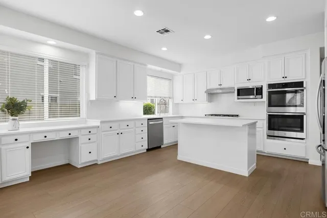 a kitchen with white cabinets stainless steel appliances and window