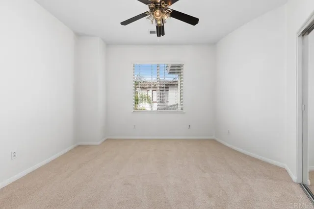 an empty room with a window and a ceiling fan