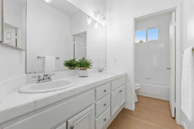 a bathroom with a double vanity sink mirror and bathtub