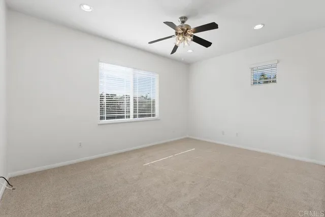 an empty room with windows and fan