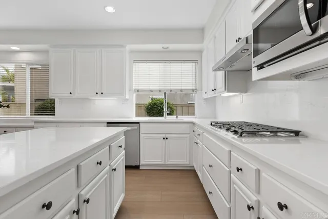 a kitchen with white cabinets stove and sink