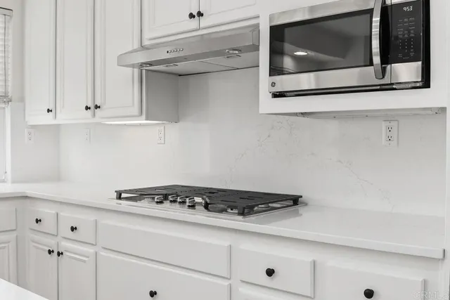 a kitchen with white cabinets and appliances