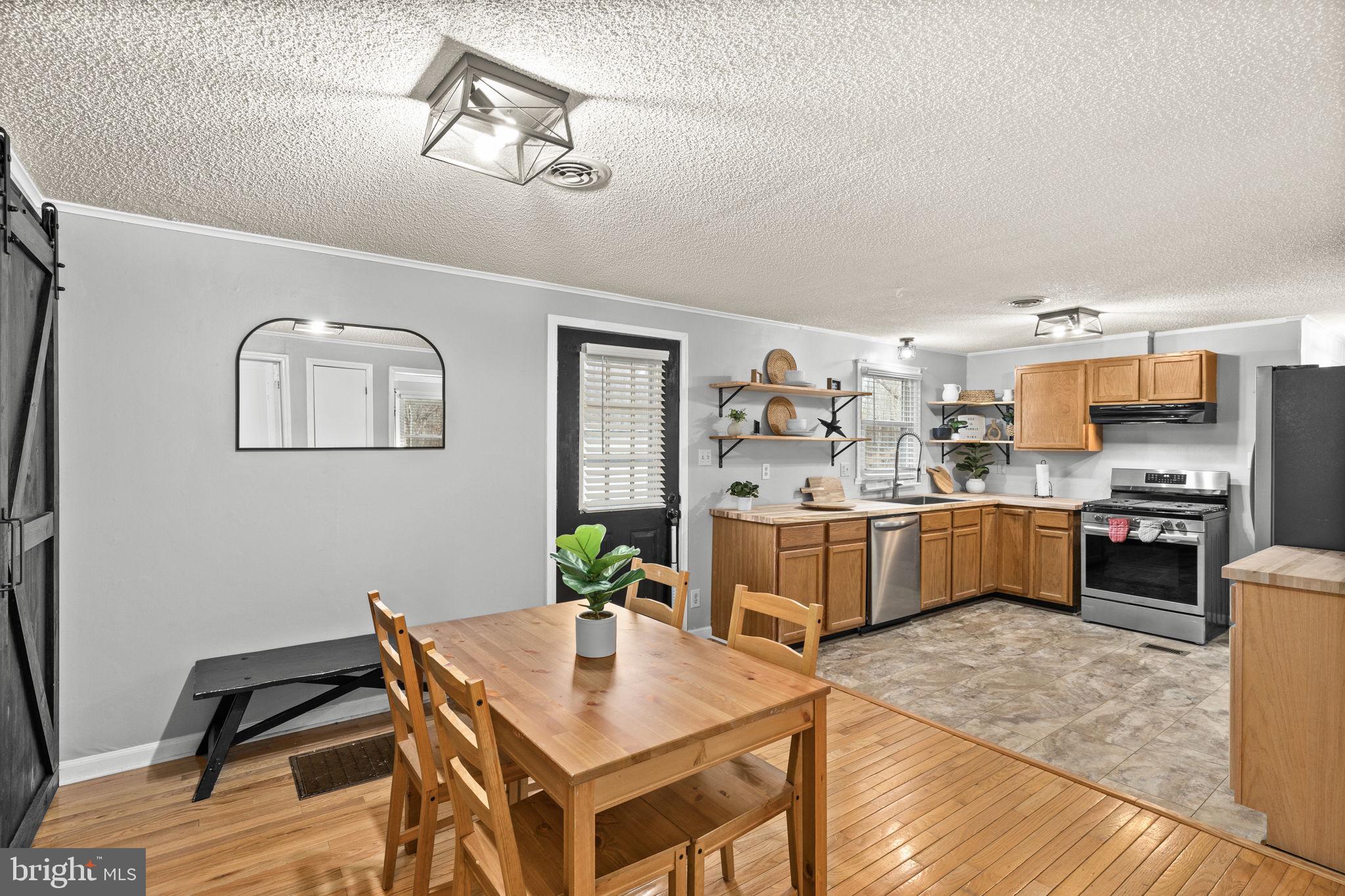 9523 Brock Road Spotsylvania, VA 22553 - Photo 15 of 44 a kitchen with stainless steel appliances kitchen island granite countertop a stove refrigerator and dining table with wooden floor