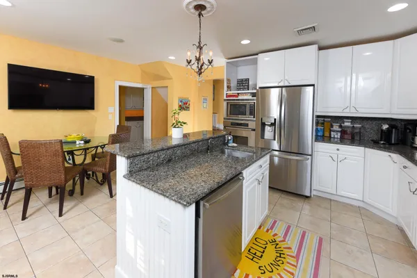 a kitchen with stainless steel appliances granite countertop a sink a stove a refrigerator cabinets and chairs