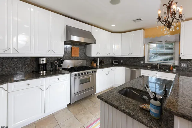 a kitchen with granite countertop white cabinets and a stove