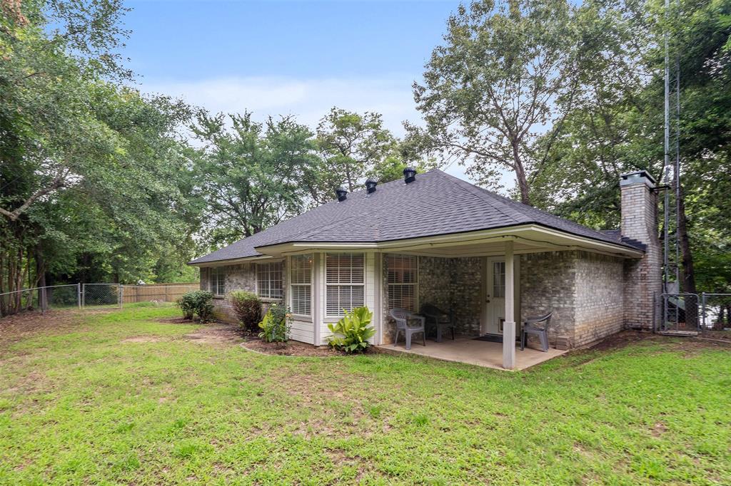 12752 Honeysuckle Circle Eustace, TX 75124 - Photo 23 of 28 Back of property featuring a chimney, a patio, a fenced backyard, roof with shingles, and a gate; internet antenna installed for better reception.