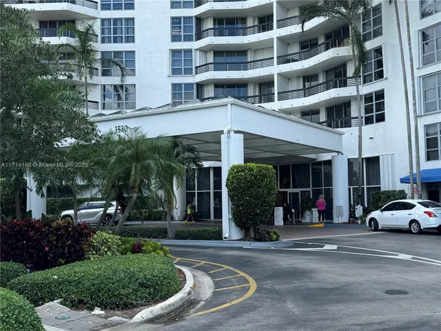 an empty room with wooden floor chandelier and windows