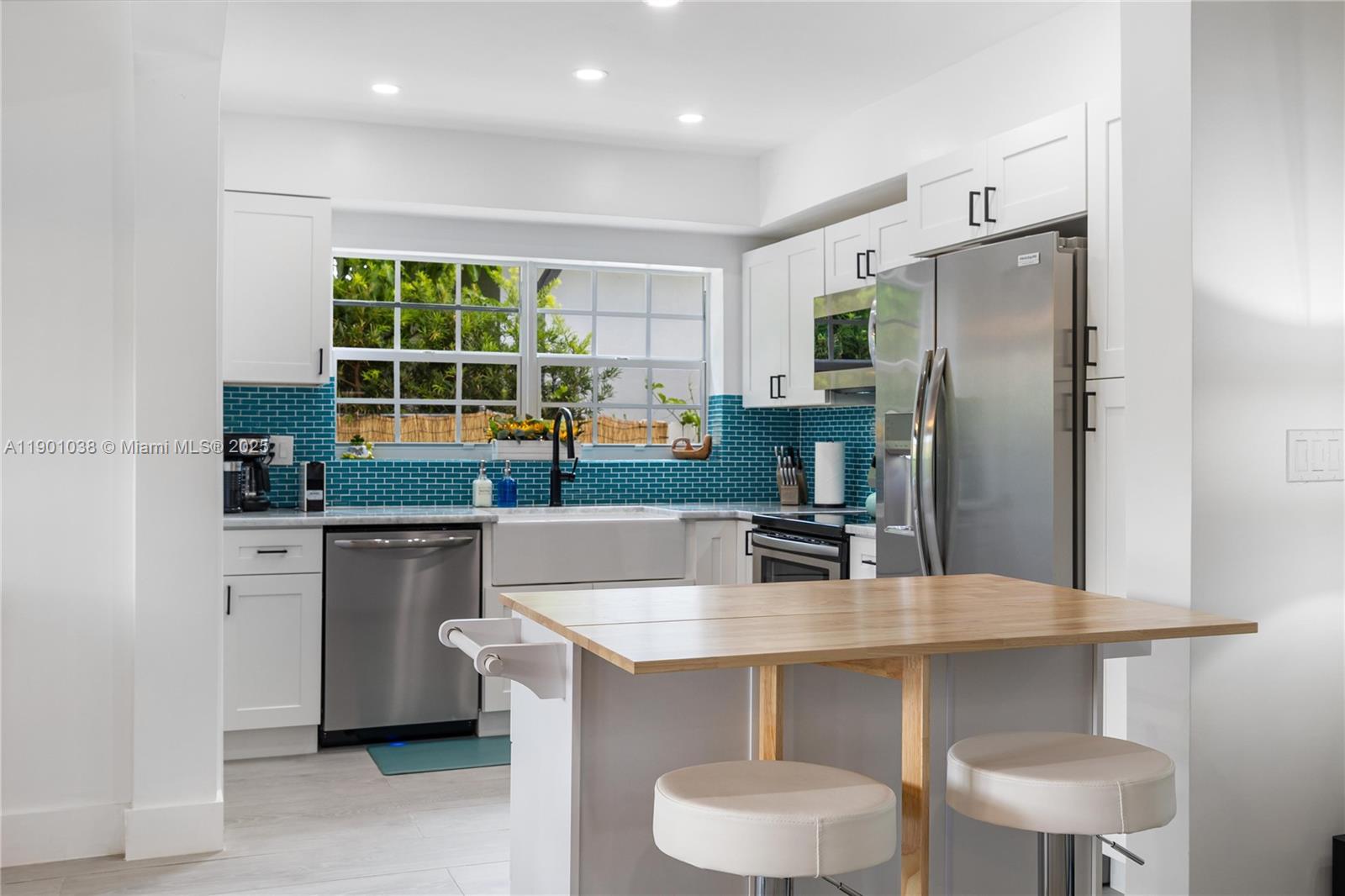 8926 Abbott Avenue Surfside, FL 33154 - Photo 9 of 30 a kitchen with a table chairs refrigerator and cabinets