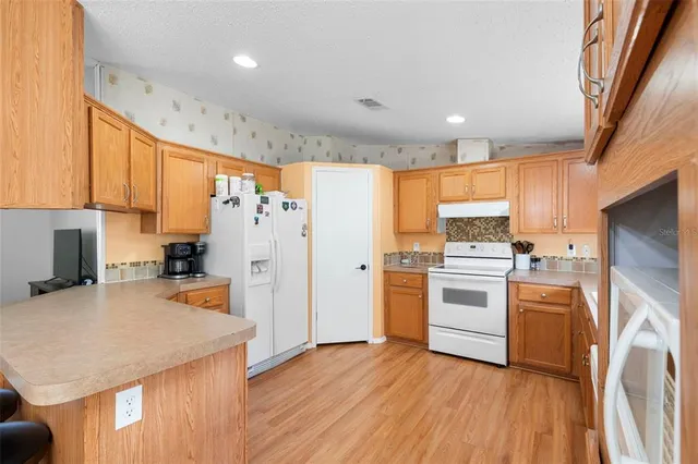 a kitchen with a refrigerator a stove top oven a sink and dishwasher with wooden floor