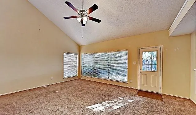 an empty room with windows and ceiling fan