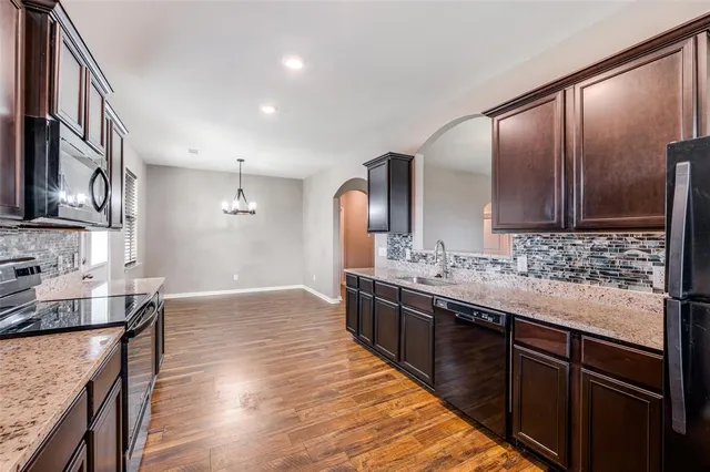 a kitchen with stainless steel appliances granite countertop a sink stove microwave and refrigerator