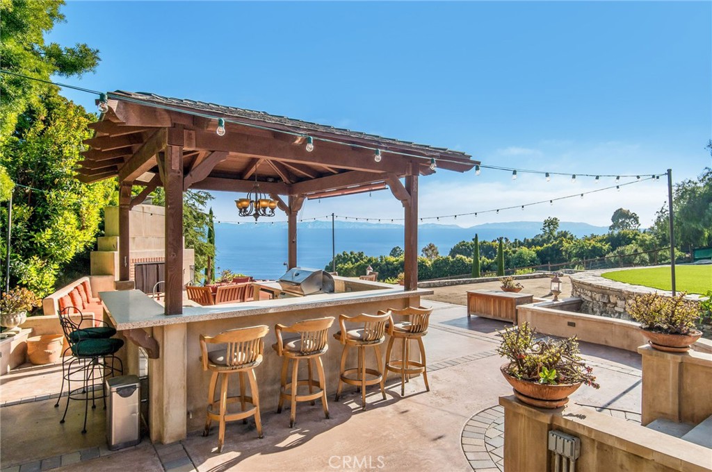 1 Thyme Place Rancho Palos Verdes, CA 90275 - Photo 28 of 35 a view of a patio with couches table and chairs under an umbrella with a small yard