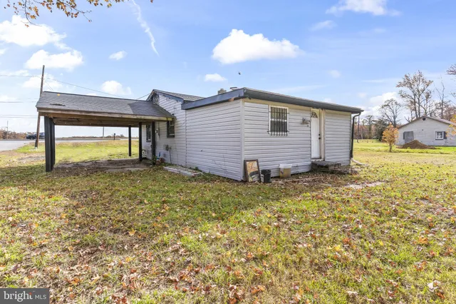 a backyard of a house with large trees and wooden fence