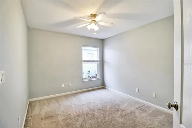 an empty room with windows and chandelier fan