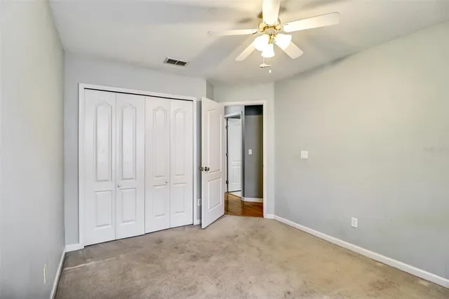 an empty room with closet and a ceiling fan