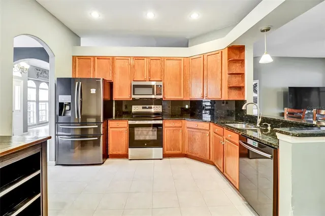 a kitchen with stainless steel appliances granite countertop a refrigerator a stove a sink and a microwave