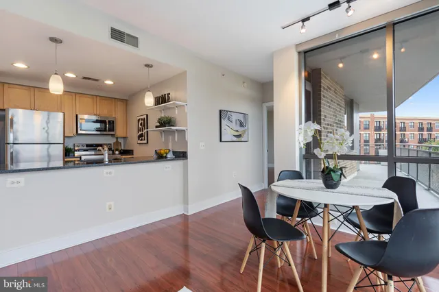 a kitchen with stainless steel appliances kitchen island granite countertop a dining table chairs and a refrigerator