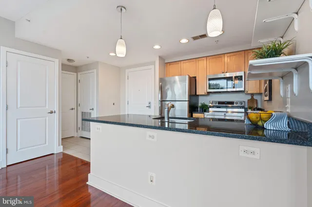 a kitchen with stainless steel appliances a stove a sink a refrigerator white cabinets and wooden floor