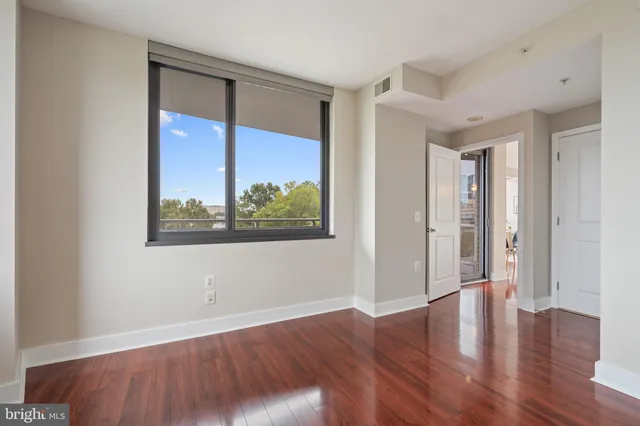 a view of an empty room with wooden floor and a window