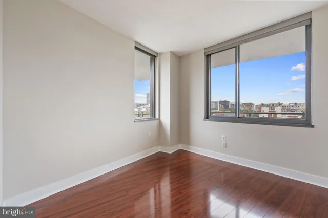 a view of an empty room with wooden floor and a window