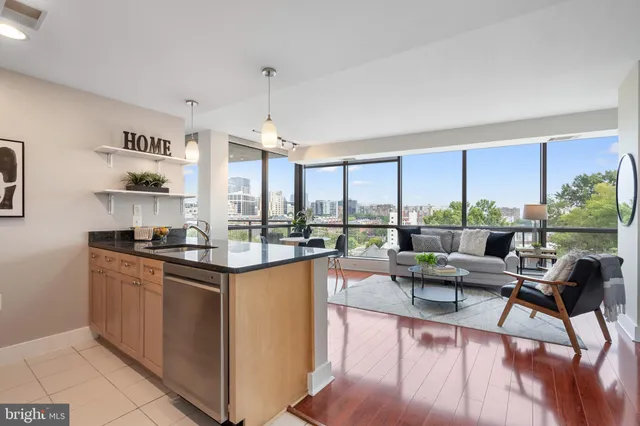 a living room with stainless steel appliances granite countertop a couch a table and chairs in it