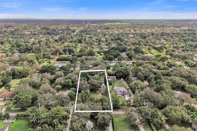 an aerial view of residential houses with outdoor space and trees