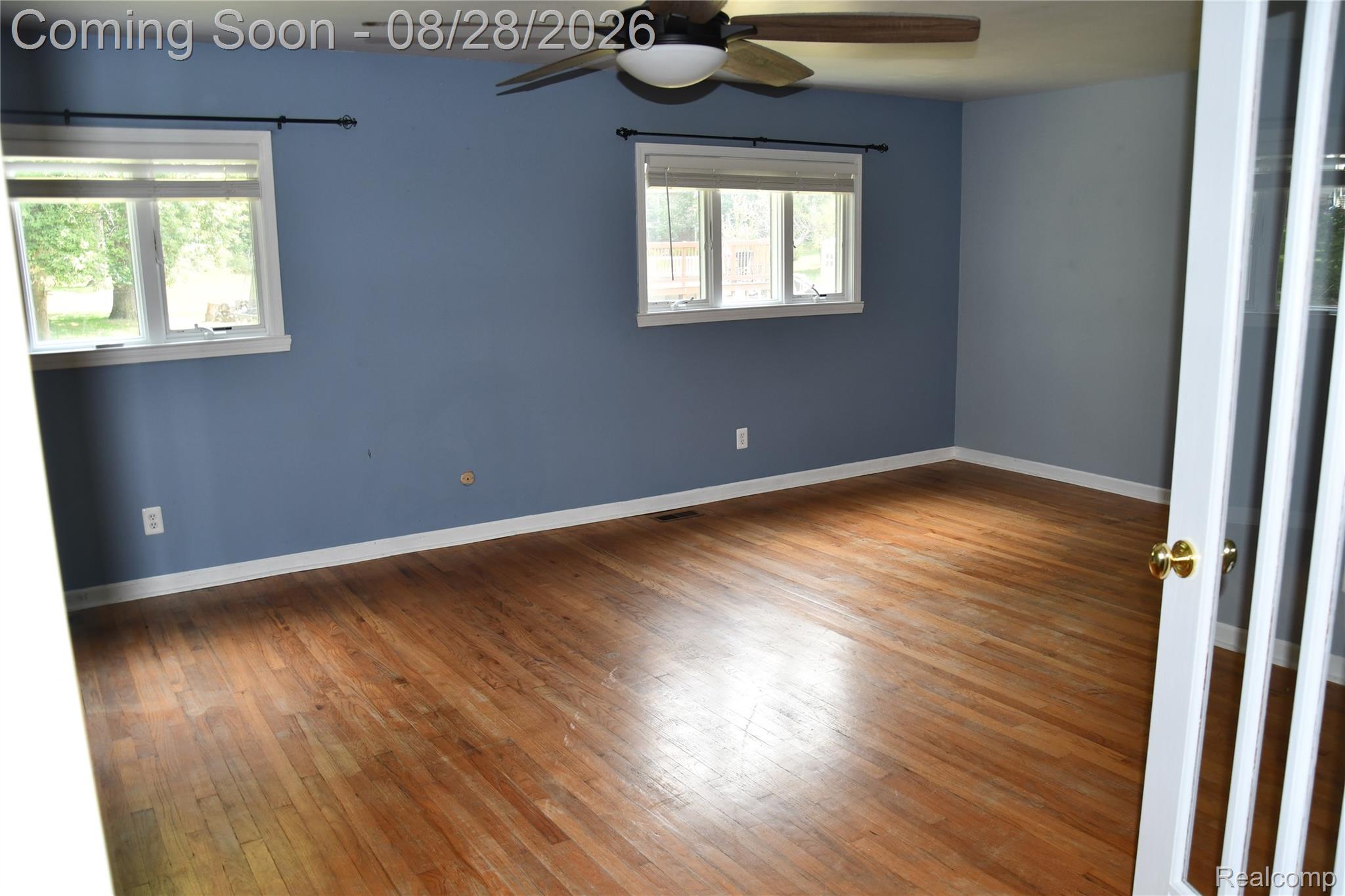 9039 Peer Road South Lyon, MI 48178 - Photo 19 of 47 Hardwood flooring, painted walls, two windows with white trim, ceiling fan, and French doors with glass panels