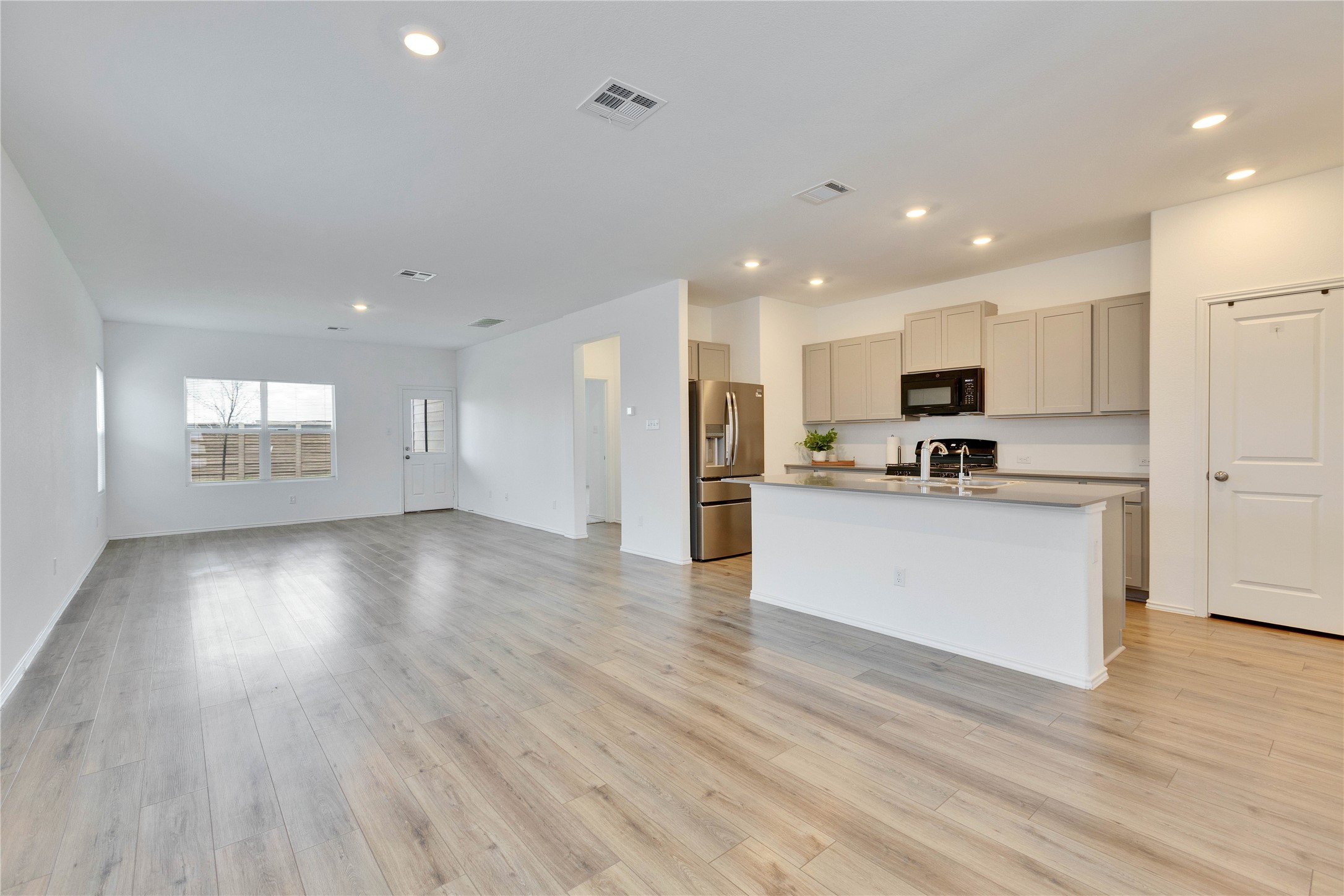 206 Canley Loop Hutto, TX 78634 - Photo 31 of 31 Kitchen with open floor plan, recessed lighting, stainless steel fridge with ice dispenser, black microwave, and an island with sink.
