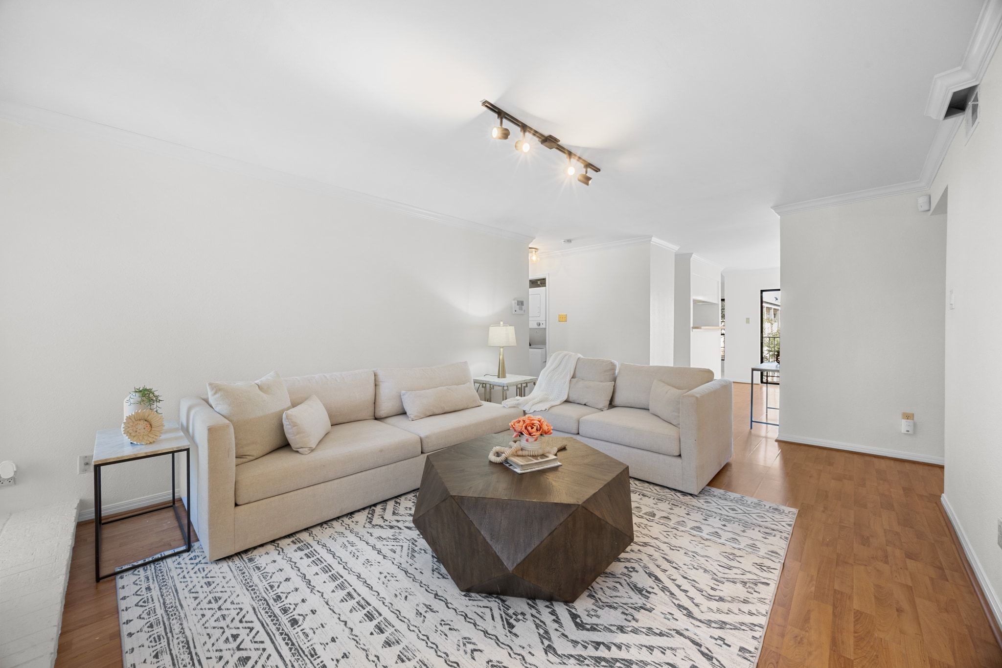 Neutral white paint, wood-look laminate flooring, and crown molding create a clean, comfortable backdrop.