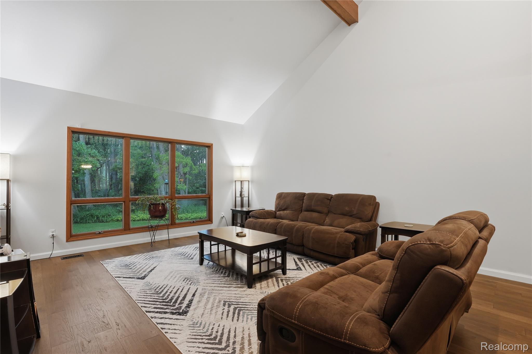 68345 Romeo Plank Road Ray, MI 48096 - Photo 28 of 52 Vaulted ceiling great room featuring expansive windows with wood-finish trim, exposed beam, and wood-finish flooring